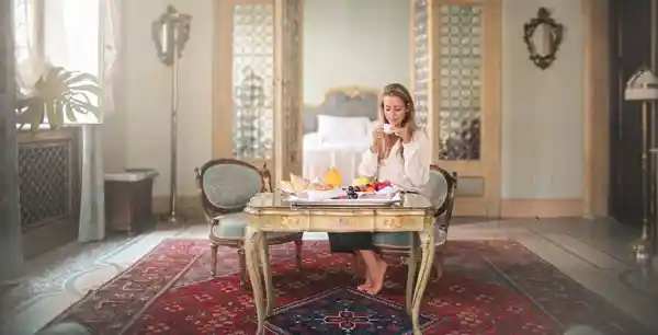 Foto de uma mulher rica tomando café da manhã em uma sala de luxo.  o amor ao mundo: Não ameis o mundo.