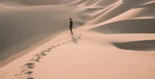 Foto de um homem andando nas dunas. Sem a santificação ninguém verá a Deus.